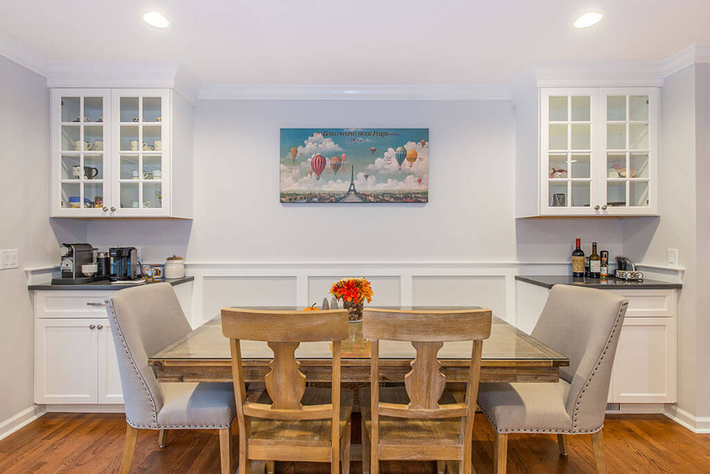 Kitchen dining area with coffee and beverage stations with white shaker cabinets and glass upper cabinets, and hardwood flooring in Randolph, NJ remodeled by JMC Home Improvement Specialists