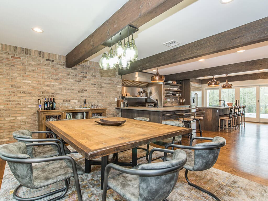 Eat in rustic open floor plan kitchen with exposed brick, industrial  range and hood, wood beams and hardwood flooring throughout in Rockaway, NJ remodeled by JMC Home Improvement Specialists