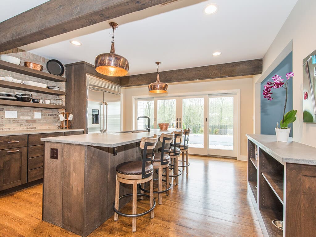 Rustic open floor plan kitchen, concrete island, open shelving with exposed brick, wood beams and hardwood flooring throughout in Rockaway, NJ remodeled by JMC Home Improvement Specialists