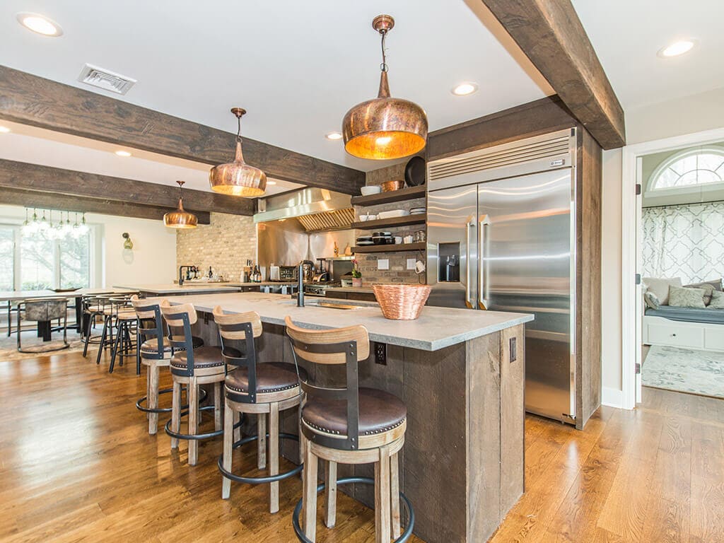 Rustic open floor plan kitchen, concrete island and peninsula, open shelving with exposed brick, industrial appliances, wood beams and hardwood flooring throughout in Rockaway, NJ remodeled by JMC Home Improvement Specialists