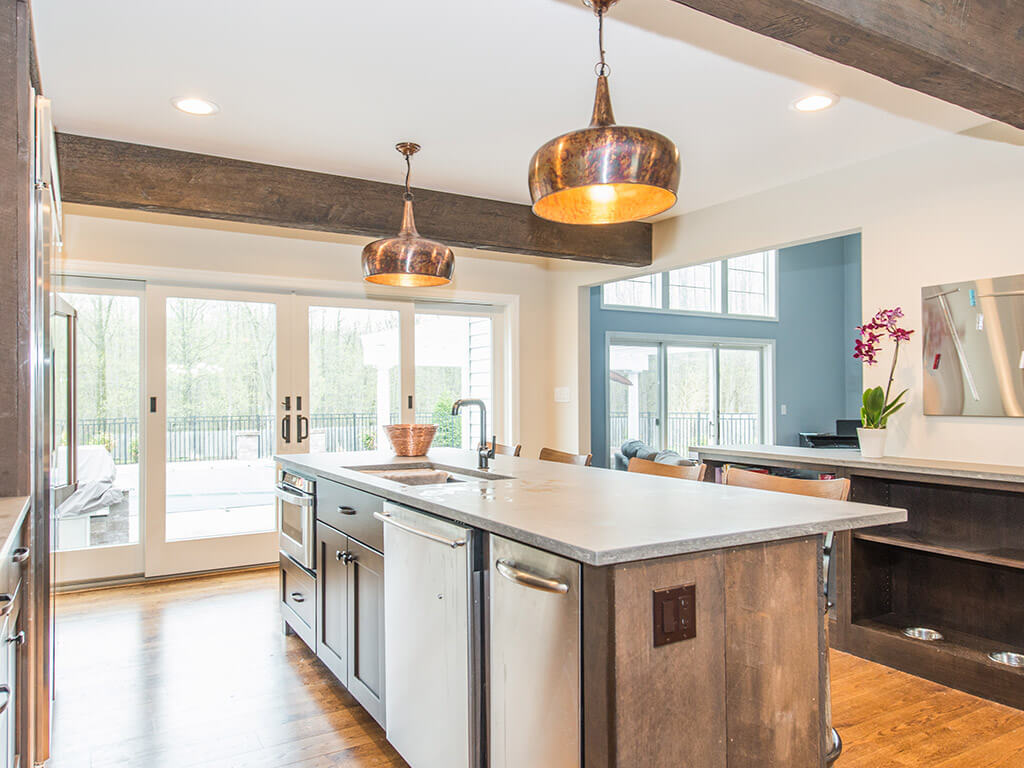 Rustic open concept kitchen, concrete island, built in dog dishes, wood beams and hardwood flooring throughout in Rockaway, NJ remodeled by JMC Home Improvement Specialists