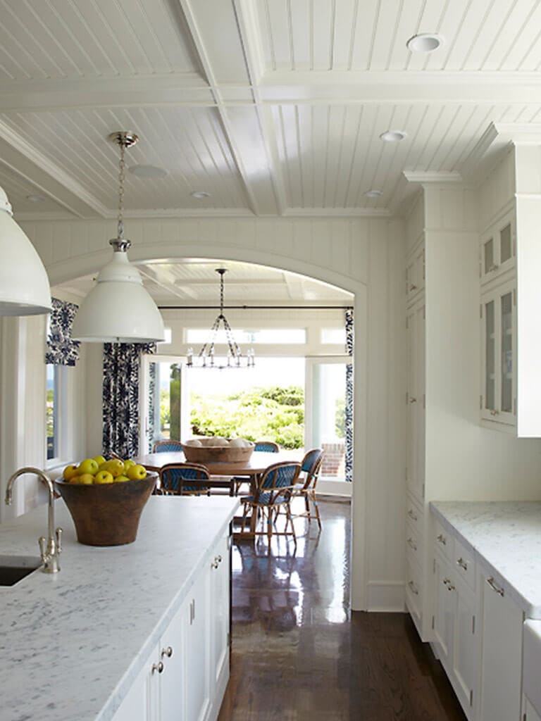 White kitchen with beadboard, white shaker double stack cabinets with glass doors, arch opening, Carrera marble counter with bar sink in island in Springlake, NJ remodeled by JMC Home Improvement Specialists