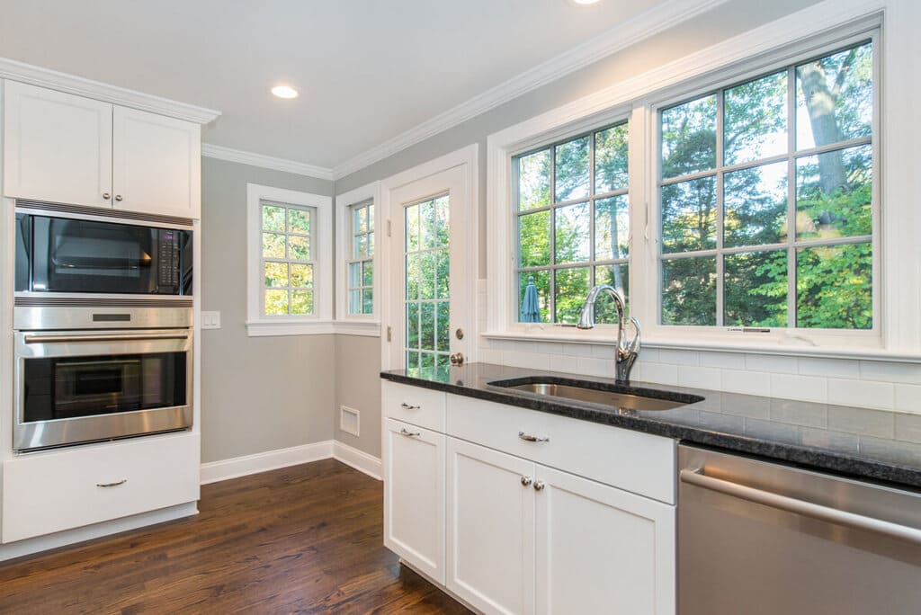 White kitchen shaker cabinets, white subway tile backsplash, black with pearl granite countertop with undermount sink and wall oven in Springfield, NJ remodeled by JMC Home Improvement Specialists