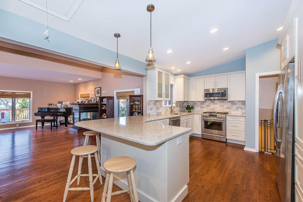 Wall removal for open floor concept kitchen with white Shaker cabinets with subway tile backsplash and hardwood floors in Summit, NJ remodeled by JMC Home Improvement Specialists