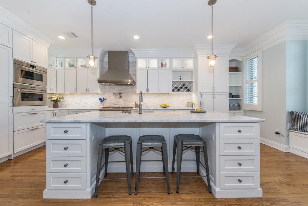 White kitchen with shaker cabinets and crown molding, marble countertops with pendant lights in Morristown, NJ remodeled by JMC Home Improvement Specialists