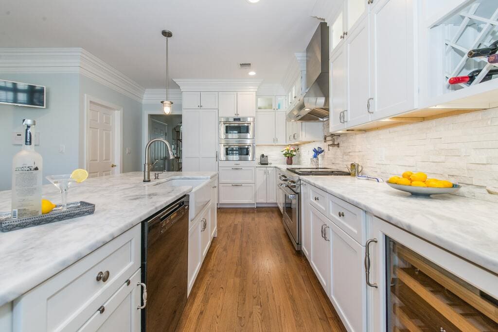 White kitchen with shaker cabinets and crown molding, marble countertops with farm sink, double ovens and panel fridge in Morristown, NJ remodeled by JMC Home Improvement Specialists