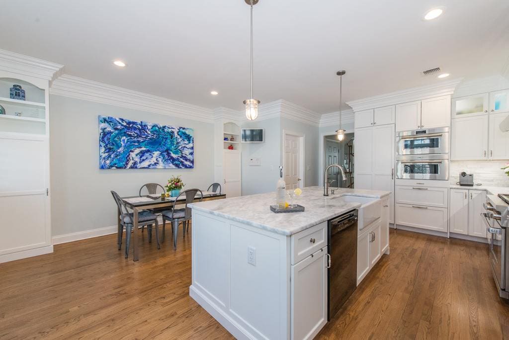 White kitchen with shaker cabinets and crown molding, marble countertops with farm sink, double ovens and panel fridge and freezer drawer in Morristown, NJ remodeled by JMC Home Improvement Specialists