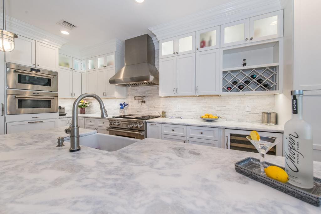 White kitchen with shaker double stack cabinets with frosted glass and crown molding, wine rack, marble countertops with farm sink in Morristown, NJ remodeled by JMC Home Improvement Specialists