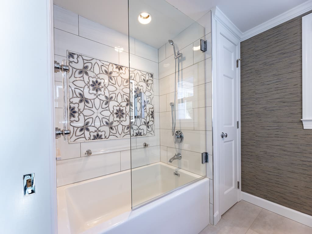 Large soaking tub with decorative grab bars and tile and glass panel shower door in Byram NJ remodeled by JMC