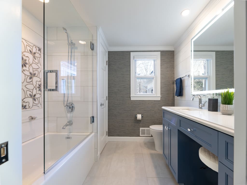 Large soaking tub with decorative grab bars and tile and glass panel shower door in Byram NJ remodeled by JMC