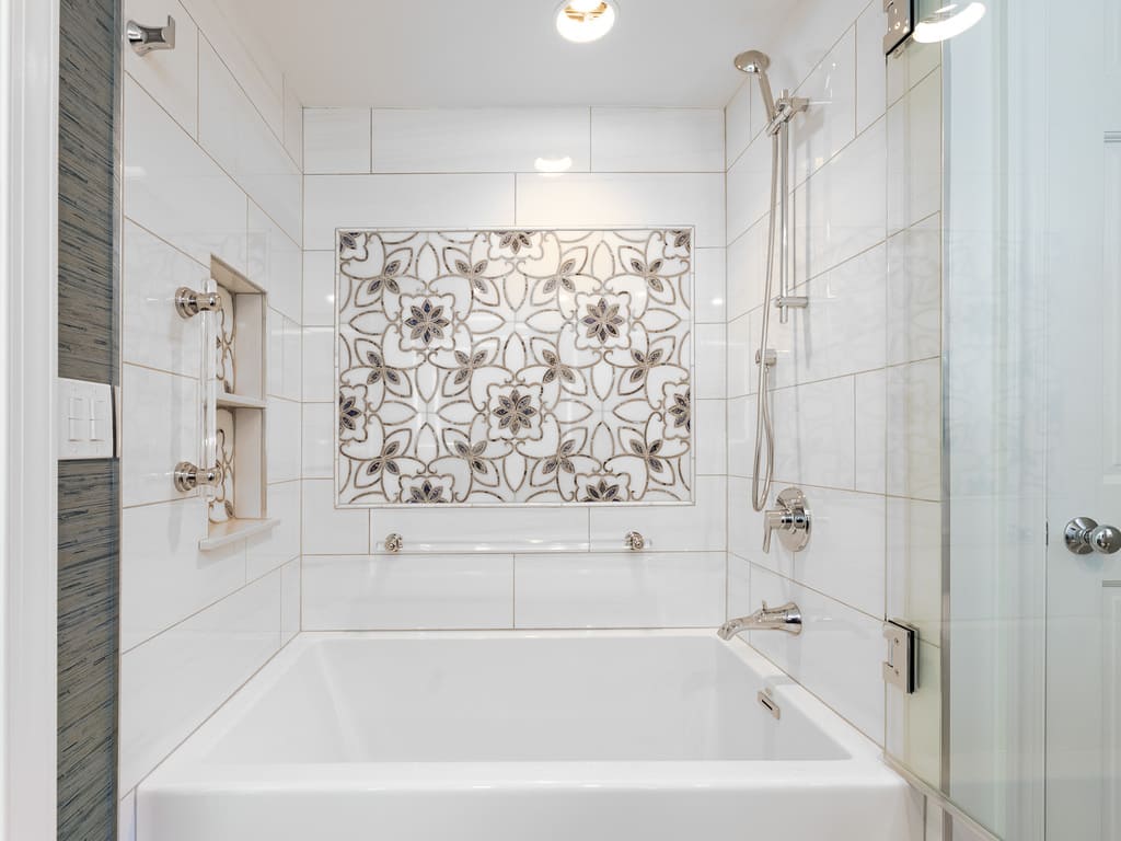 Large soaking tub with decorative grab bars and tile and glass panel shower door in Byram NJ remodeled by JMC