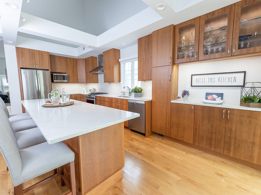 Open kitchen with glass cabinets, kitchen island, flat panel cabinets, open bookcase, custom ceiling beams in Somerset County renovated by JMC Home Improvement Specialists